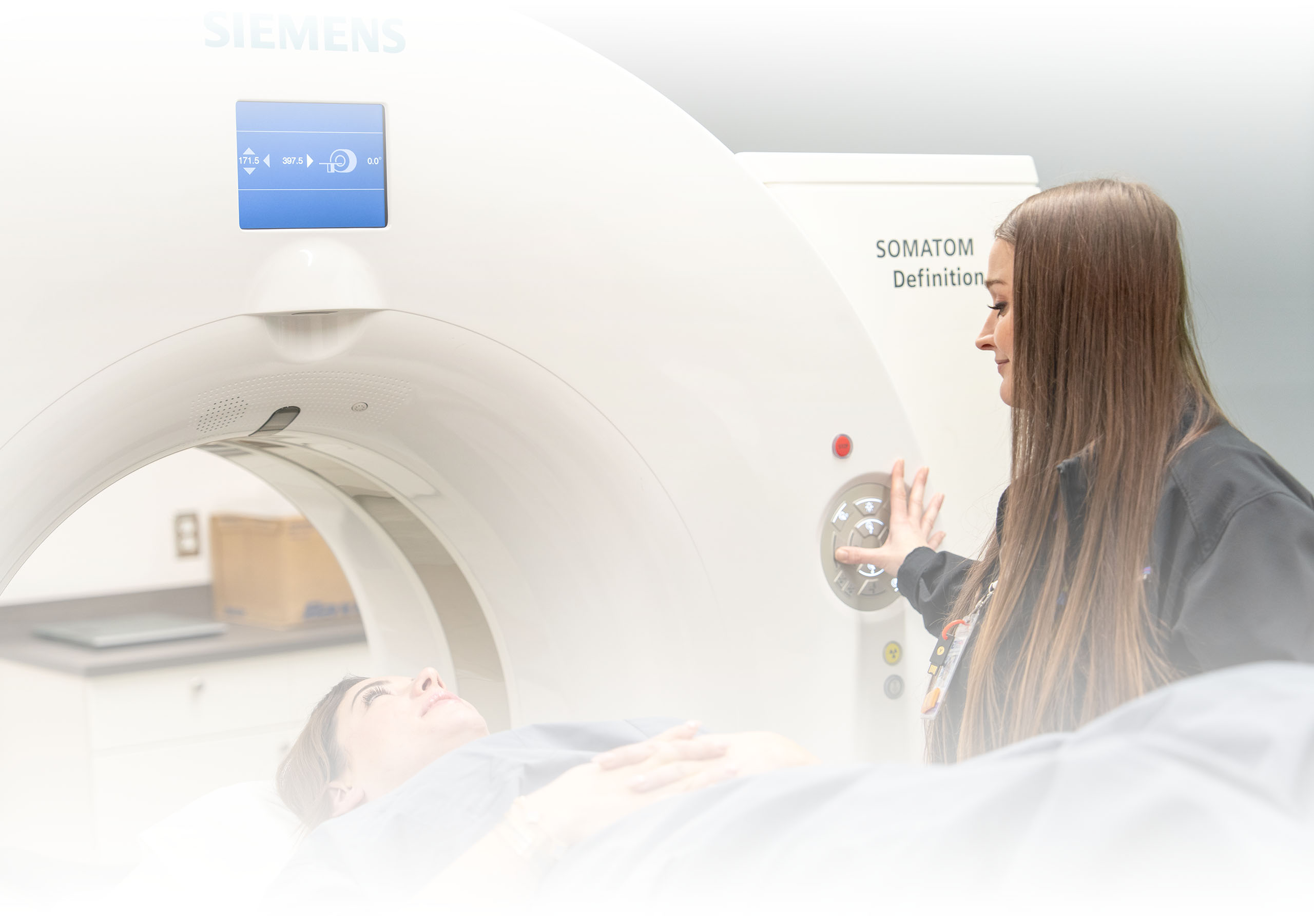 A technical helping a woman with a CT scan