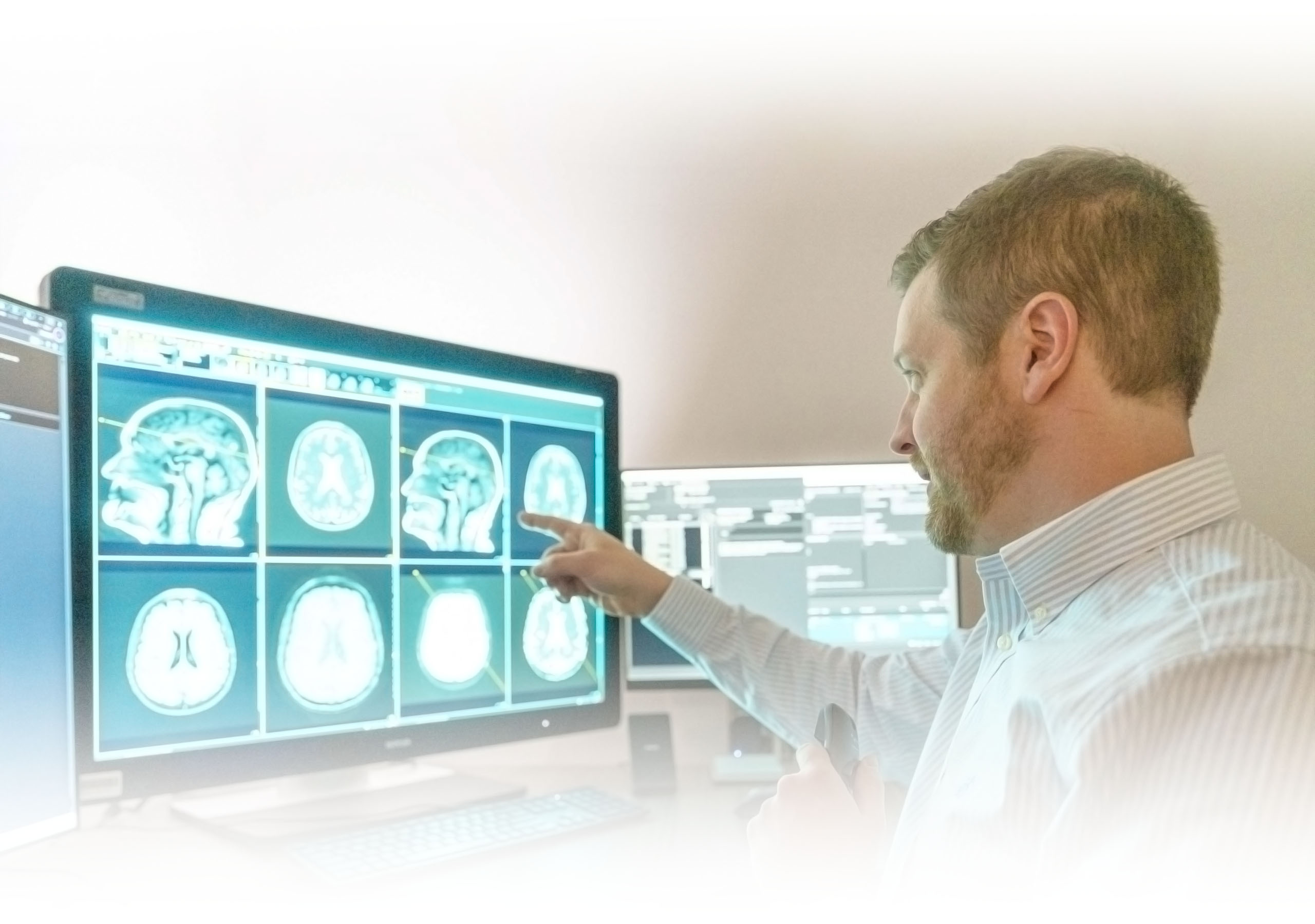 A radiologist looking at brain scans on a monitor
